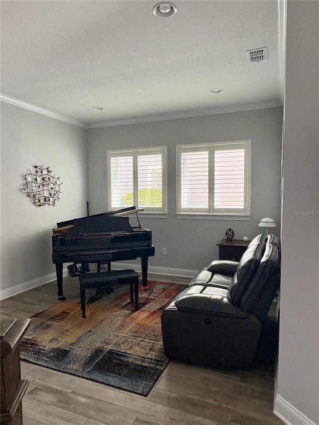 living area with baseboards, visible vents, ornamental molding, and wood finished floors