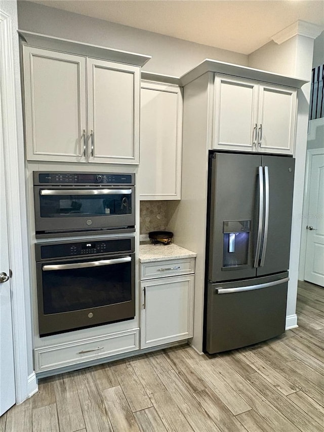 kitchen with light wood-type flooring, double wall oven, and stainless steel fridge with ice dispenser