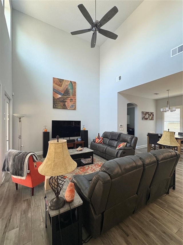 living area with baseboards, visible vents, arched walkways, and wood finished floors