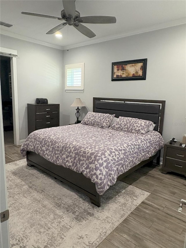 bedroom with ceiling fan, visible vents, wood finished floors, and ornamental molding