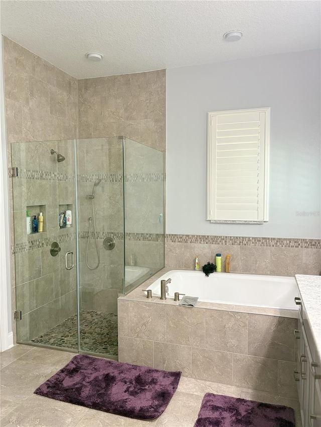 bathroom with a shower stall, a textured ceiling, a bath, and vanity