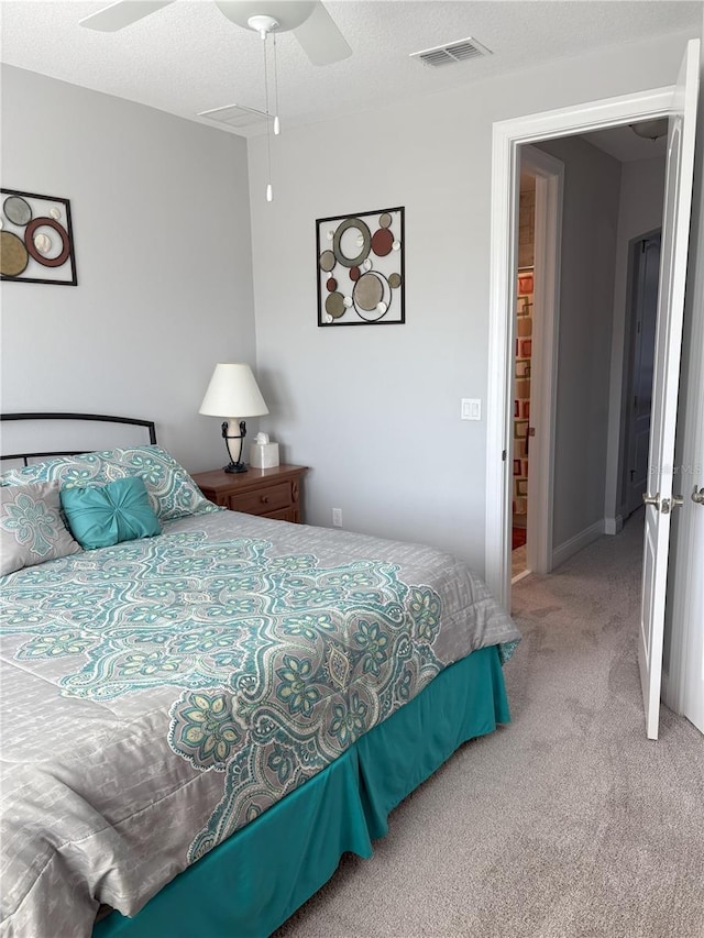 carpeted bedroom with a ceiling fan, visible vents, and a textured ceiling