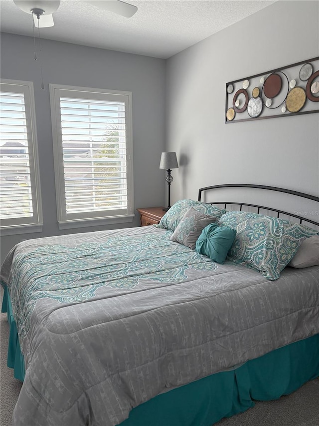 carpeted bedroom featuring multiple windows, ceiling fan, and a textured ceiling