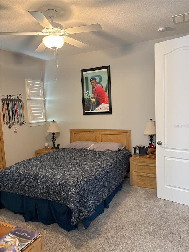 bedroom with ceiling fan, visible vents, a textured ceiling, and light colored carpet