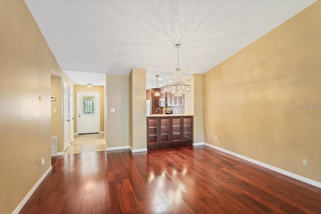 interior space featuring dark wood-style floors, baseboards, and a notable chandelier