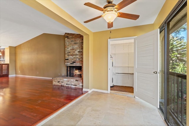 unfurnished living room featuring baseboards, a ceiling fan, lofted ceiling, wood finished floors, and a brick fireplace