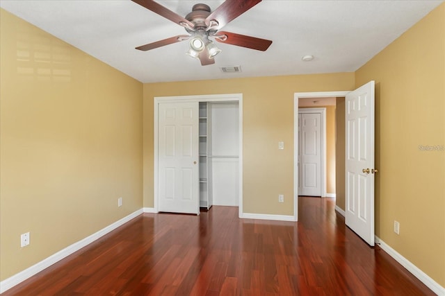 unfurnished bedroom with a closet, visible vents, ceiling fan, wood finished floors, and baseboards