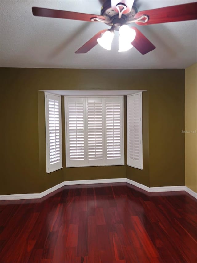 unfurnished room with a ceiling fan, baseboards, and wood finished floors