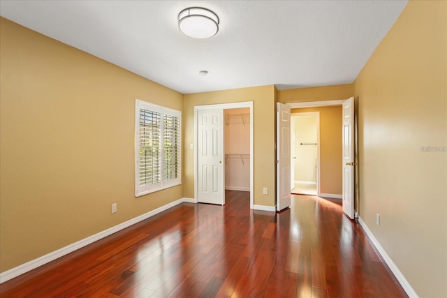 unfurnished bedroom with dark wood-style floors, baseboards, and a closet