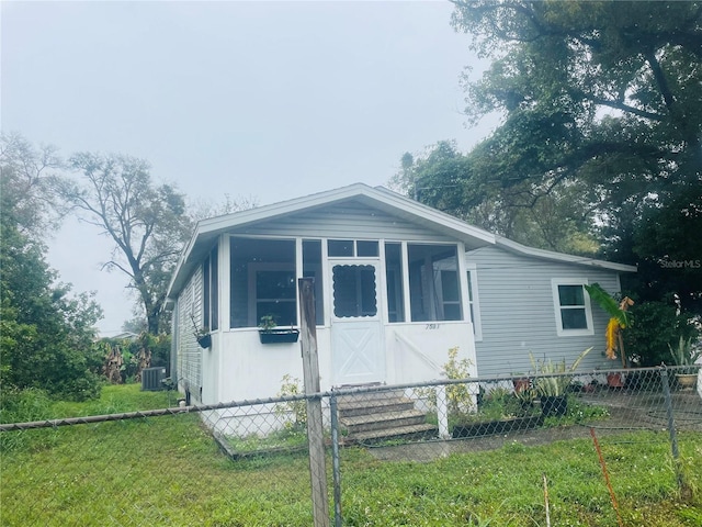 view of front of house featuring a front lawn, cooling unit, and fence