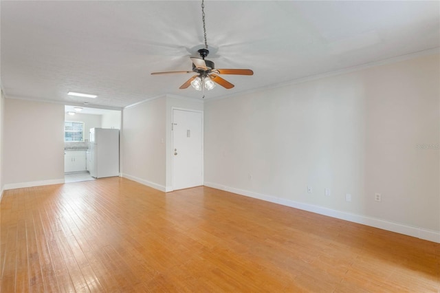 spare room featuring light wood-style floors, ceiling fan, and crown molding