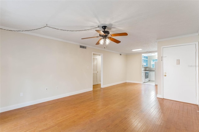 empty room featuring light wood-type flooring, visible vents, crown molding, and baseboards
