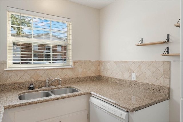 kitchen with decorative backsplash, white cabinets, dishwasher, and a sink
