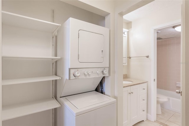 laundry area featuring laundry area, stacked washing maching and dryer, and light tile patterned flooring