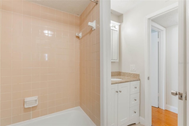 bathroom featuring wood finished floors, shower / tub combination, and vanity
