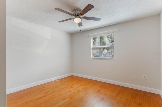 spare room featuring light wood-type flooring, ceiling fan, baseboards, and a textured ceiling