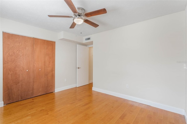 unfurnished bedroom featuring a ceiling fan, visible vents, baseboards, a closet, and light wood finished floors