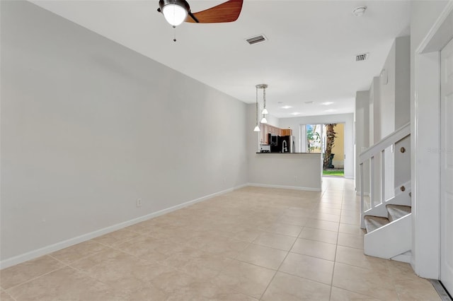 unfurnished room with visible vents, stairway, ceiling fan, and baseboards