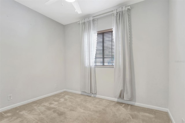 spare room with ceiling fan, baseboards, and light colored carpet