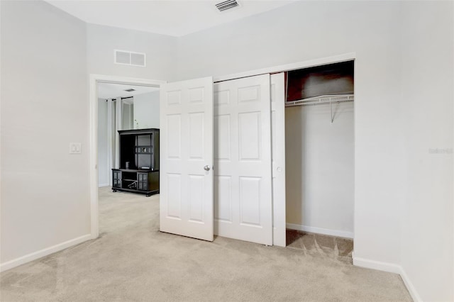 unfurnished bedroom featuring baseboards, visible vents, a closet, and light colored carpet