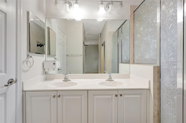 full bathroom with double vanity, a sink, and a shower with shower door