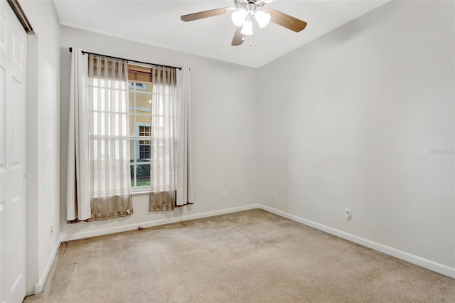 empty room with light carpet, plenty of natural light, a ceiling fan, and baseboards