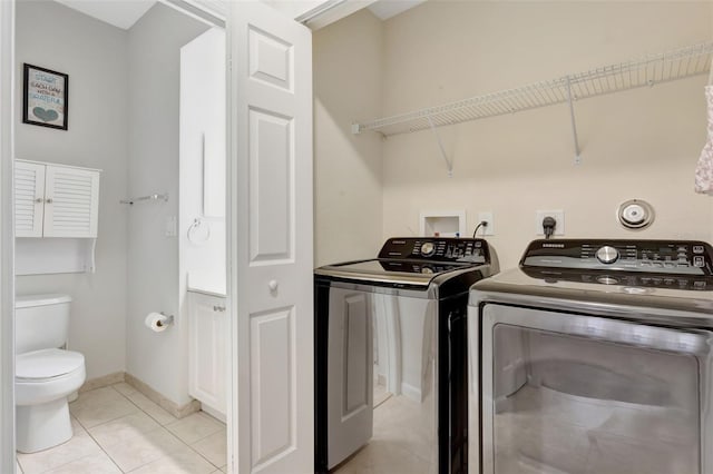 laundry area featuring baseboards, laundry area, light tile patterned flooring, and washer and dryer