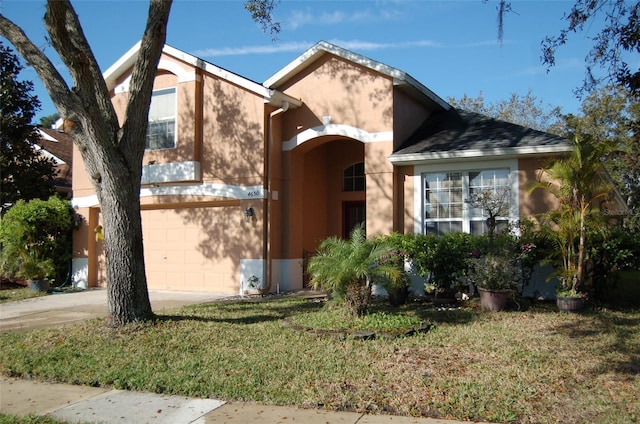 view of front of home featuring driveway, an attached garage, a front lawn, and stucco siding