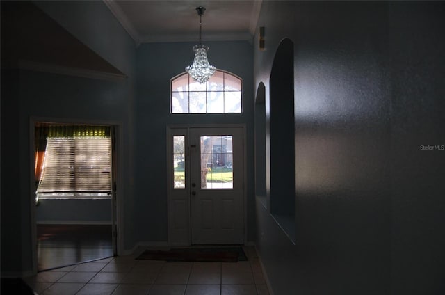 entrance foyer with an inviting chandelier, tile patterned flooring, ornamental molding, and baseboards