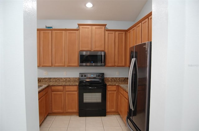 kitchen with electric range, stainless steel microwave, stone countertops, and freestanding refrigerator