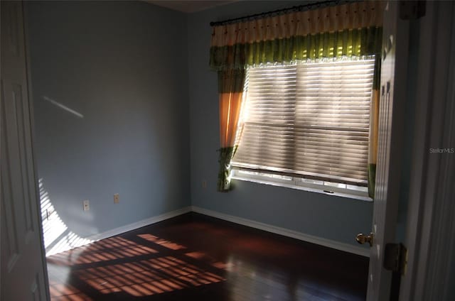 unfurnished room featuring wood-type flooring and baseboards