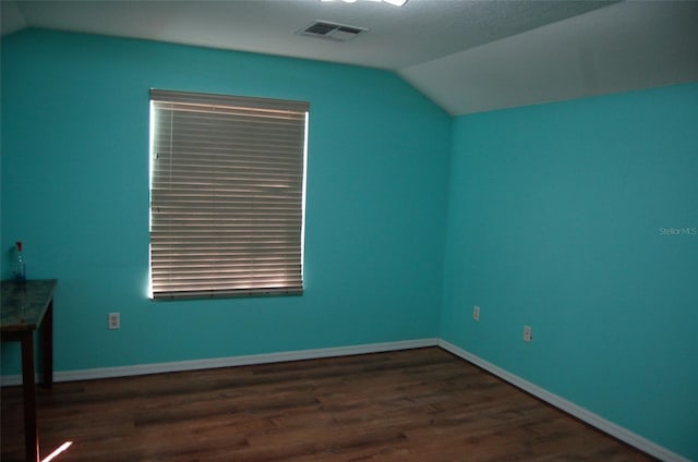 interior space with vaulted ceiling, wood finished floors, visible vents, and baseboards