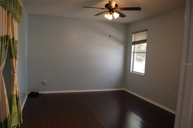 empty room featuring ceiling fan, baseboards, and dark wood finished floors