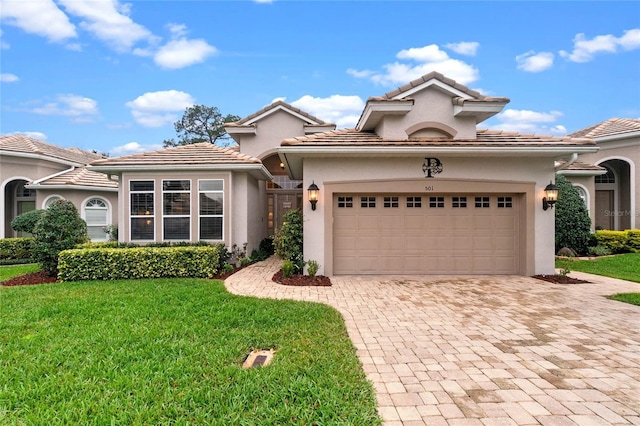 mediterranean / spanish-style home with a garage, a front lawn, decorative driveway, and stucco siding