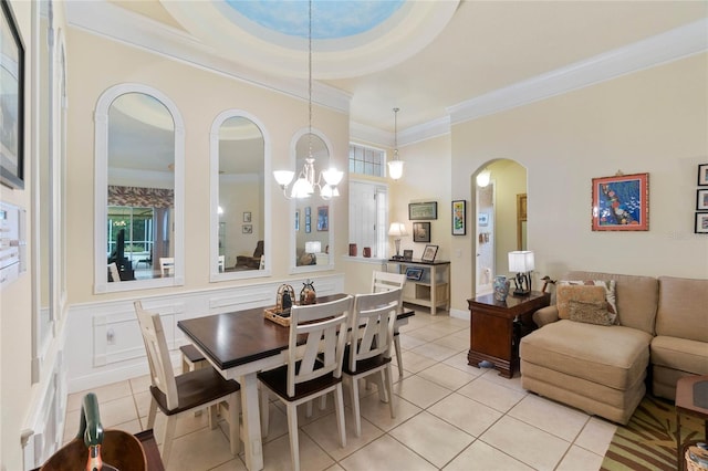 dining area featuring arched walkways, wainscoting, ornamental molding, and light tile patterned flooring