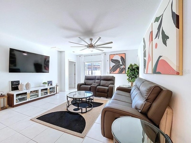 living room with a ceiling fan, light tile patterned flooring, and a textured ceiling