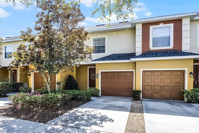 view of property featuring an attached garage, driveway, a shingled roof, and stucco siding