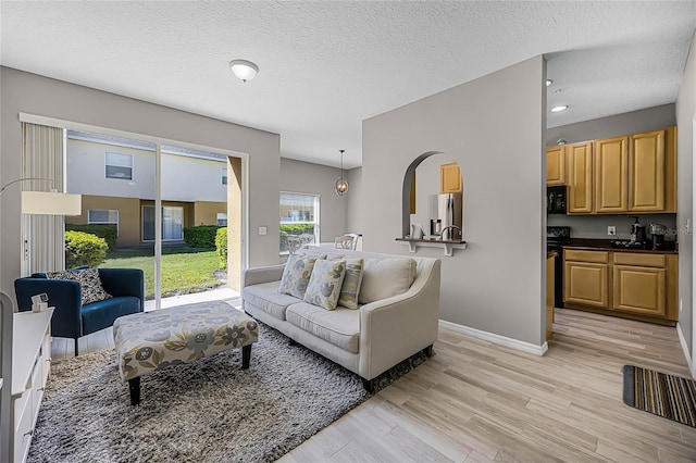 living area featuring light wood-style floors, baseboards, and a textured ceiling