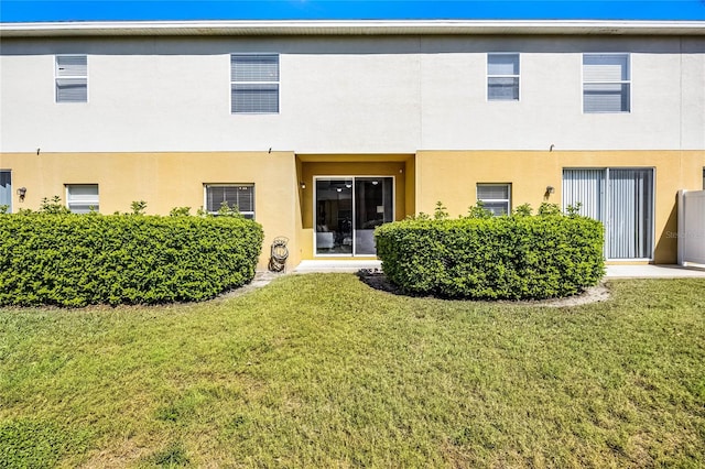 rear view of property with a lawn and stucco siding