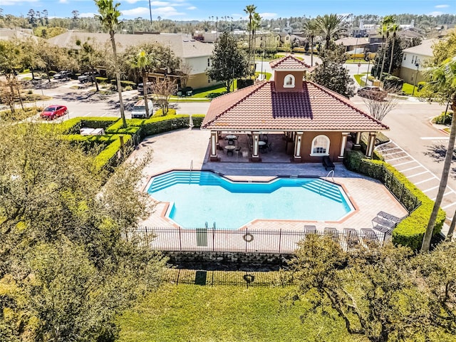 pool with a patio area, fence, and a residential view