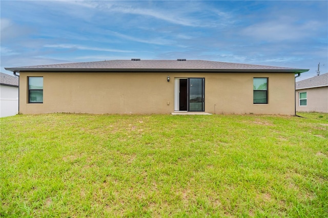 rear view of property with a yard and stucco siding