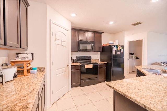 kitchen featuring visible vents, light tile patterned flooring, a sink, independent washer and dryer, and black appliances