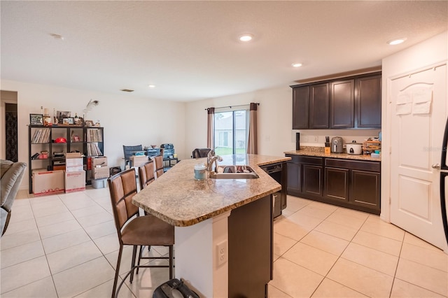 kitchen with a breakfast bar, open floor plan, a kitchen island with sink, a sink, and dishwasher