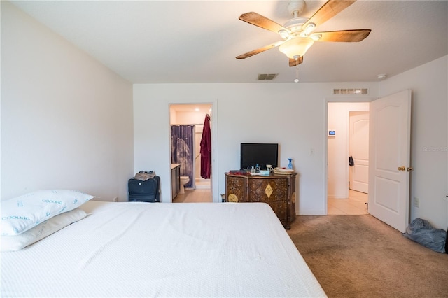 bedroom with a ceiling fan, ensuite bath, visible vents, and light colored carpet