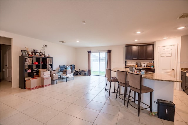 kitchen featuring stone counters, recessed lighting, visible vents, and a breakfast bar area