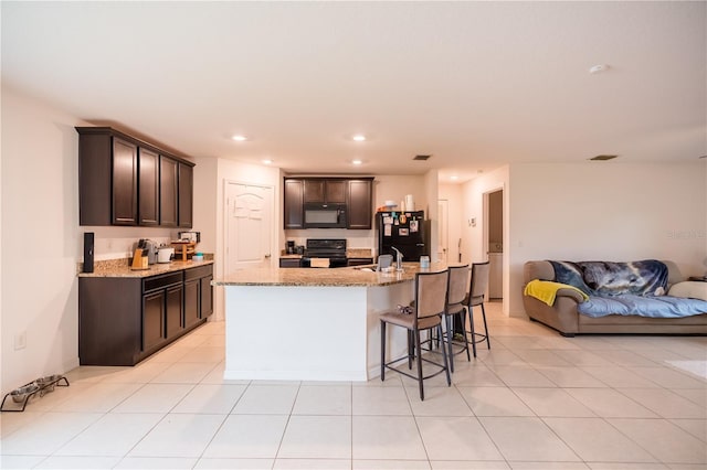 kitchen featuring dark brown cabinetry, black appliances, open floor plan, and recessed lighting