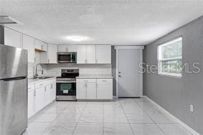 kitchen with stainless steel appliances, light countertops, and white cabinets