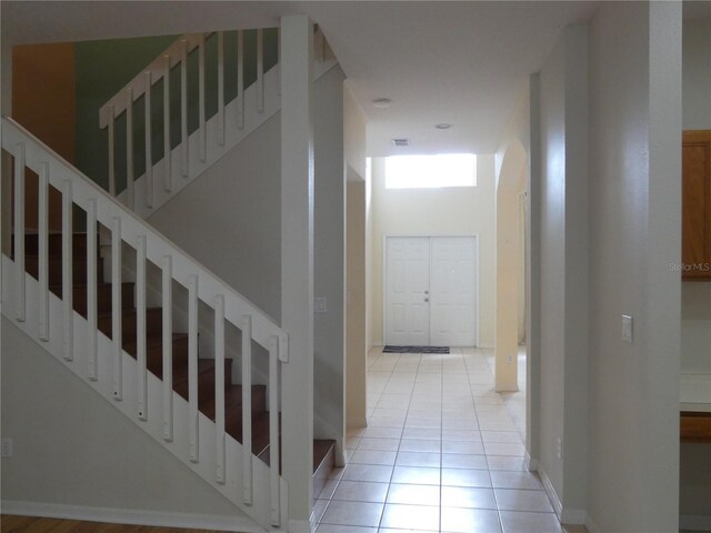 stairway featuring tile patterned flooring, a towering ceiling, and baseboards