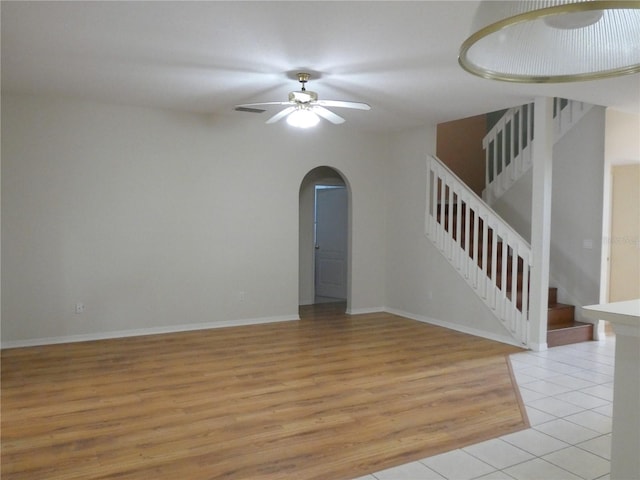 unfurnished room with arched walkways, visible vents, stairway, a ceiling fan, and light wood-style floors