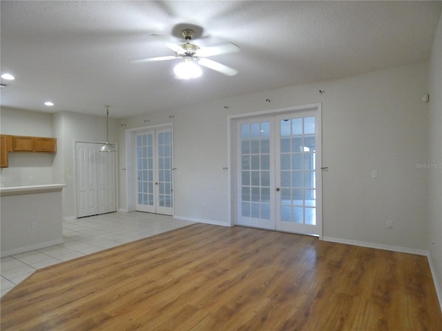 unfurnished room with a ceiling fan, light wood-type flooring, french doors, and baseboards